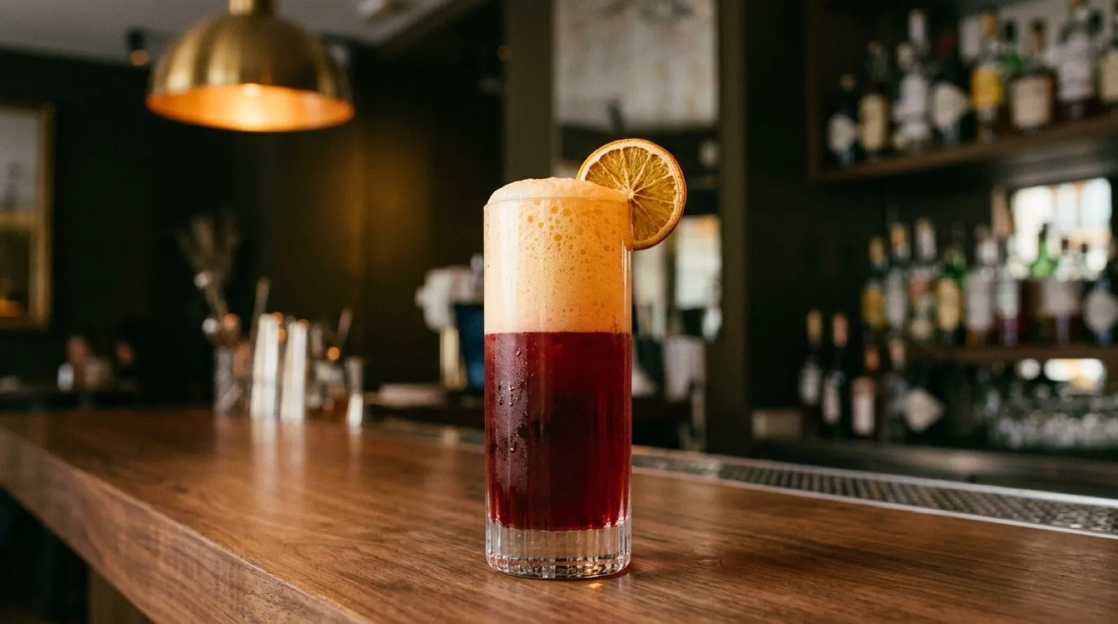 STILLROOM Madrid’s Garibaldi Fermentado: Campari with lacto-fermented orange citrus foam in a highball glass, black olive and arena gold palette