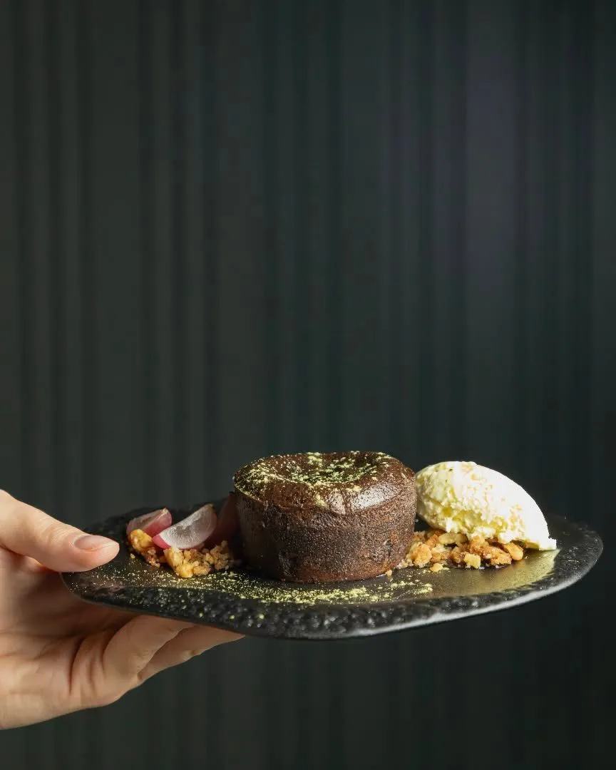 A hand holds the chocolate coulant with Stillroom ice cream