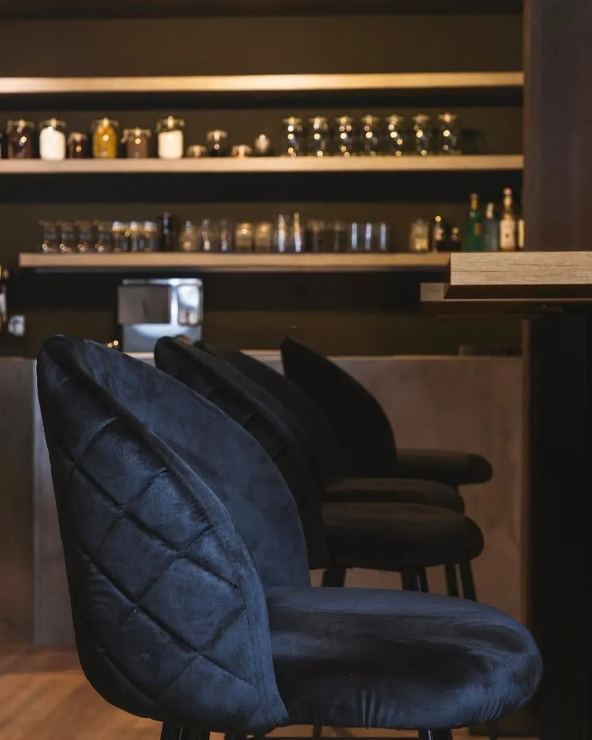 Upholstered stools next to the Stillroom bar, with the wall of jars in the background