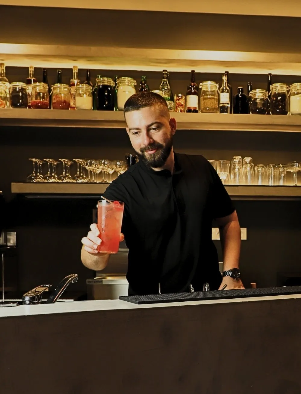 El bartender de Stillroom sirviendo un spritz en la barra, con la pared de tarros al fondo