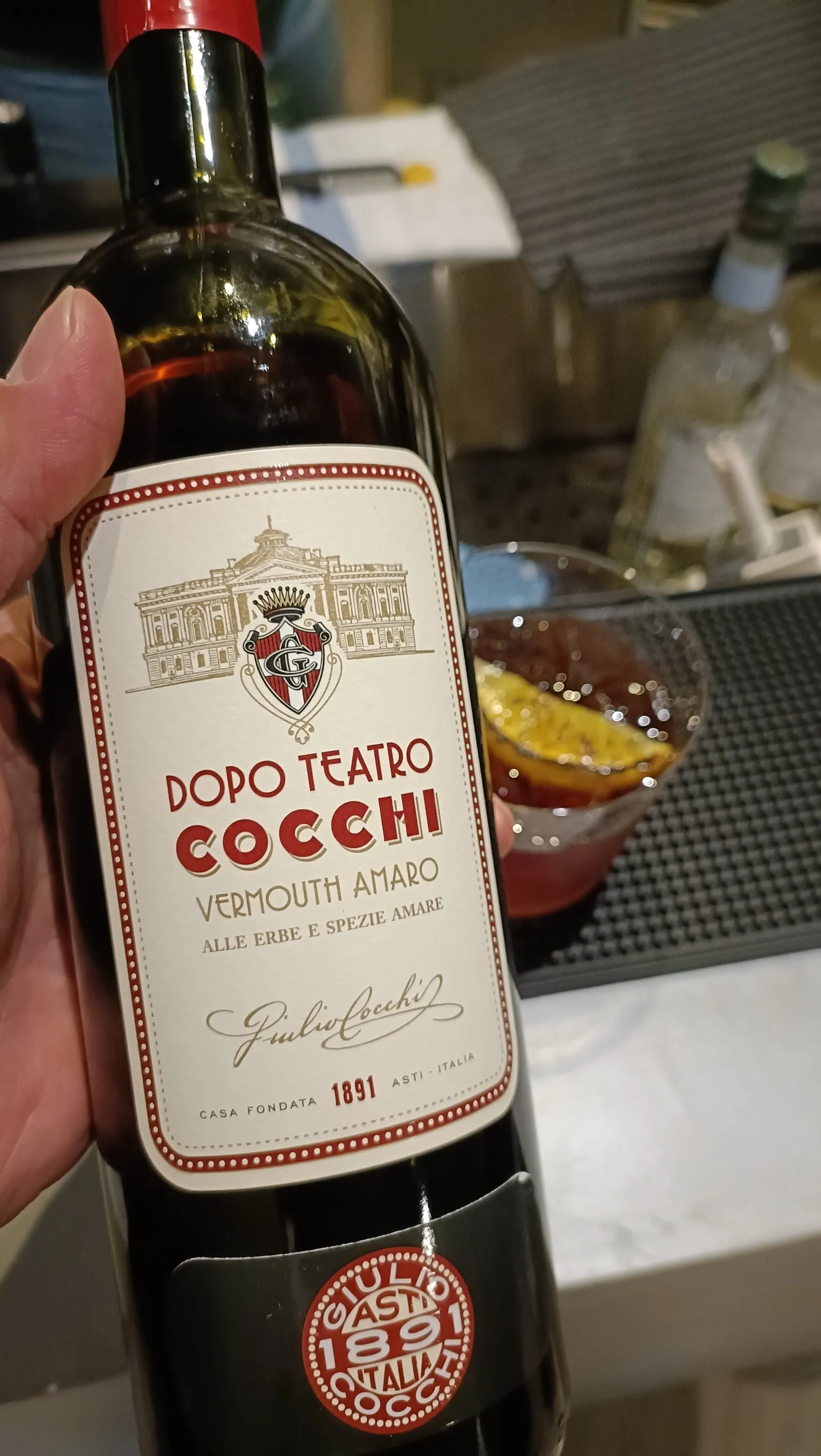 Botella de Cocchi Dopo Teatro, el vermouth amaro de la carta, junto a un vermut servido