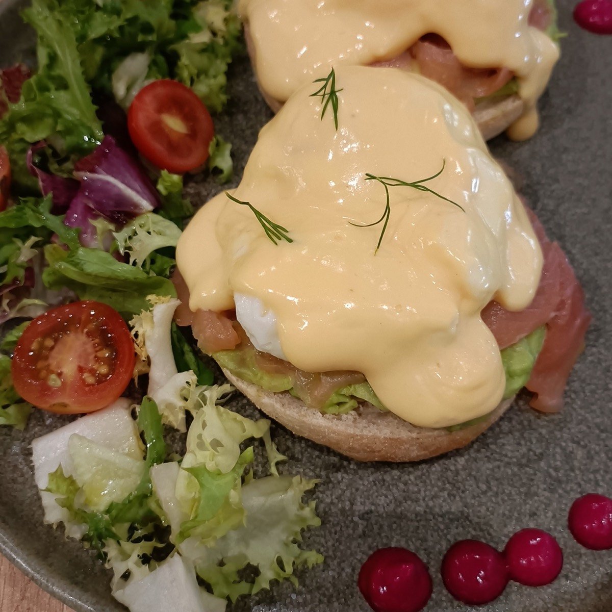 Plato de huevos benedictinos en Madrid: dos benedictinos con holandesa, ensalada fresca y puntos de crema de remolacha y mango en el brunch de Stillroom, junto al Retiro